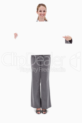 Smiling bank employee holding and pointing at blank sign