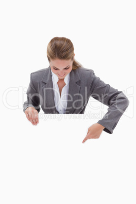Bank employee pointing down at blank sign in her hands