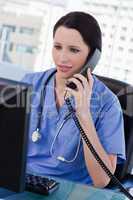 Portrait of a female doctor on the phone while using a monitor