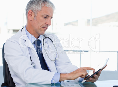 Serious doctor working with a tablet computer