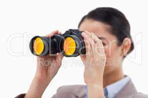Brunette businesswoman looking through binoculars