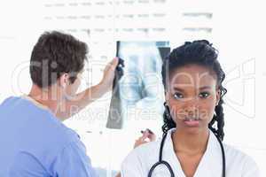 Male doctor looking at a of X-ray while his colleague is posing