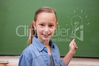 Smiling schoolgirl pointing at a bulb