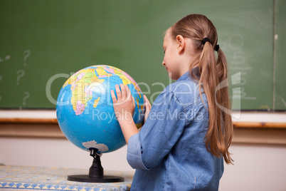 Focused schoolgirl looking at a globe