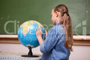 Focused schoolgirl looking at a globe