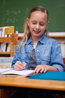 Portrait of a happy schoolgirl writing