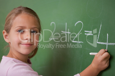 Smiling schoolgirl writing a number