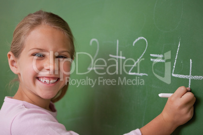 Happy schoolgirl writing a number