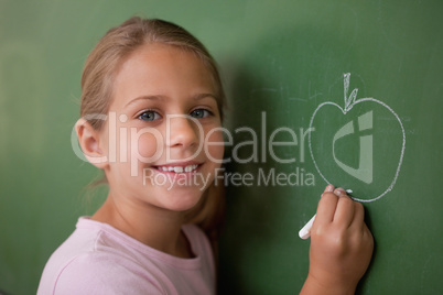 Smiling schoolgirl drawing an apple