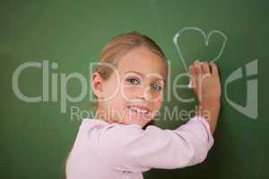 Smiling schoolgirl drawing a heart