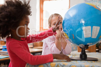 Happy schoolgirls looking at a globe