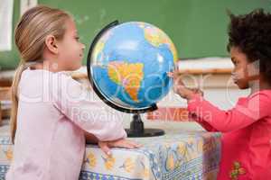 Smiling schoolgirls looking at a globe