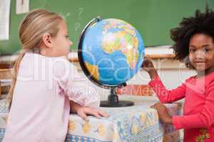 Cute schoolgirls looking at a globe