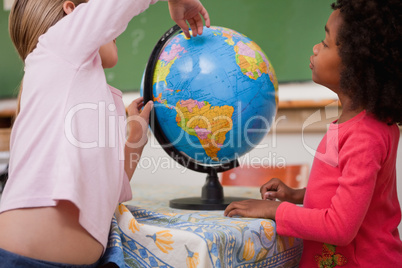 Cute little schoolgirls looking at a globe