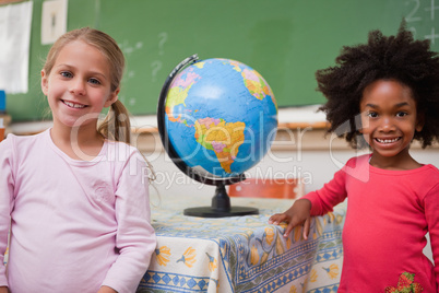 Cute schoolgirls posing with a globe