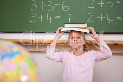 Smiling schoolgirl holding her book on her head
