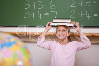 Cute schoolgirl holding her book on her head