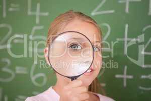 Cute schoolgirl looking through a magnifying glass