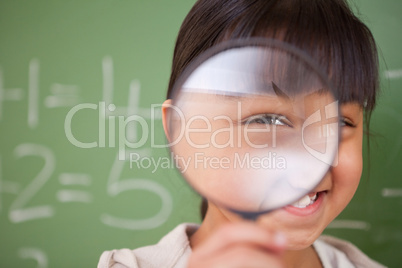 Close up of a cute schoolgirl looking through a magnifying glass