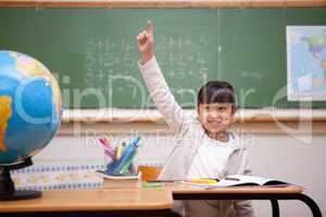Smiling schoolgirl raising her hand to answer a question