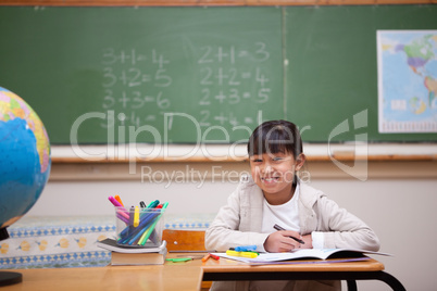 Smiling schoolgirl drawing on a coloring book