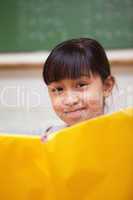 Portrait of a smiling schoolgirl reading