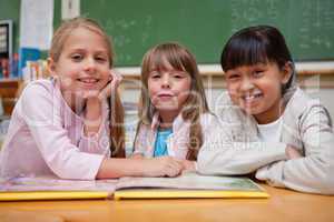 Smiling schoolgirls reading a fairy tale to their classmate