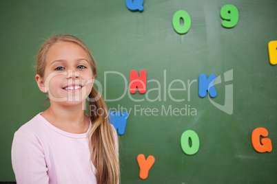 Young schoolgirl posing in front of a blackboard
