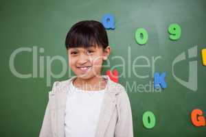 Happy schoolgirl posing in front of a blackboard