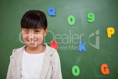 Smiling schoolgirl posing in front of a blackboard