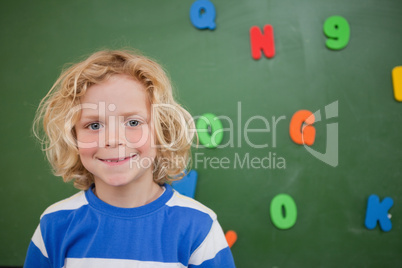 Schoolboy posing in front of a blackboard