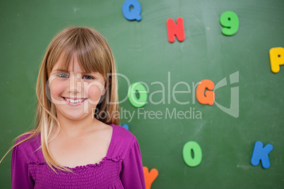 Little schoolgirl posing in front of a blackboard