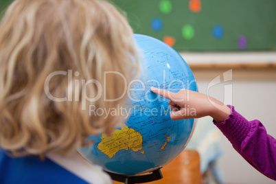 Finger of a little girl showing a country to a classmate