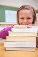 Portrait of a smiling schoolgirl posing with a stack of books