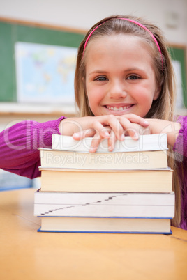 Portrait of a happy schoolgirl posing with a stack of books