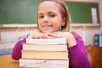 Happy schoolgirl posing with a stack of books