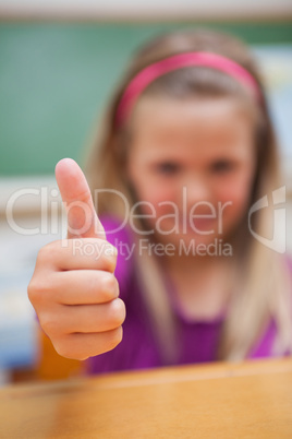 Portrait of a cute schoolgirl with the thumb up