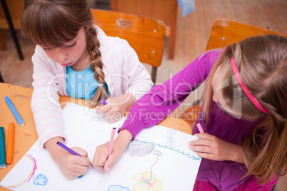 Schoolgirls drawing in a coloring book