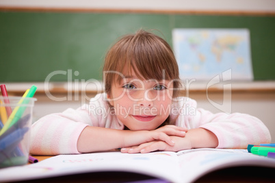 Smiling schoolgirl leaning on a desk