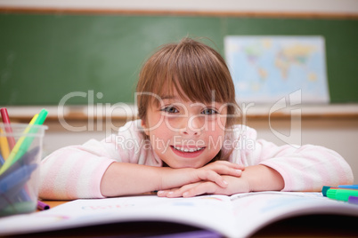 Happy schoolgirl leaning on a desk