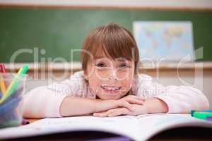 Happy schoolgirl leaning on a desk