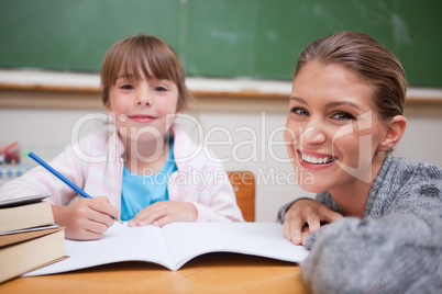 Schoolgirl writing with her teacher