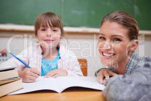 Schoolgirl writing with her teacher