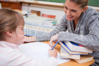 Schoolgirl writing with her smiling teacher
