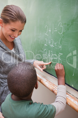 Portrait of a beautiful teacher and a pupil making an addition