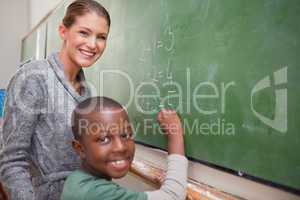Smiling teacher and a pupil making an addition