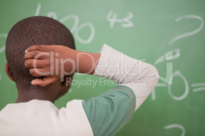 Schoolboy thinking with his hand on his head