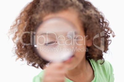 Cute girl looking through a magnifying glass