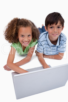 Portrait of children using a notebook while lying on the floor