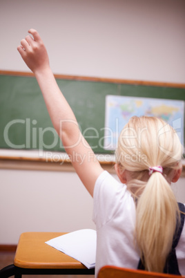 back view of a schoolgirl raising her hand